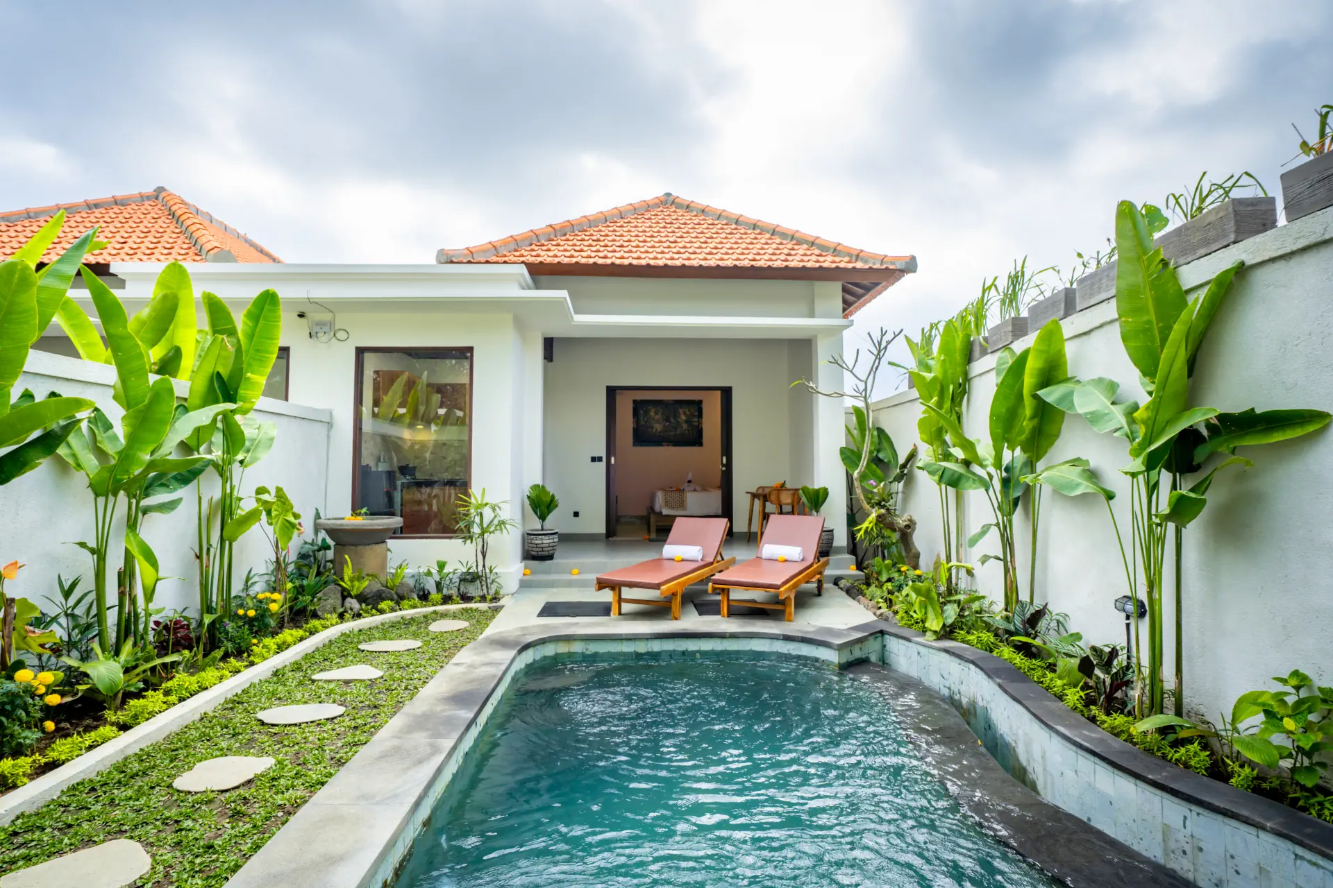 Infinity pool and lush tropical garden at The Jatu Ubud, a modern private villa in Ubud, Bali